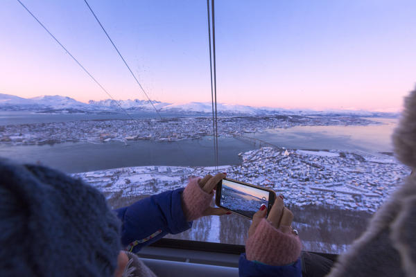 Tourist takes picture with smartphone from the cable car, Fjellheisen,Troms county, Norway