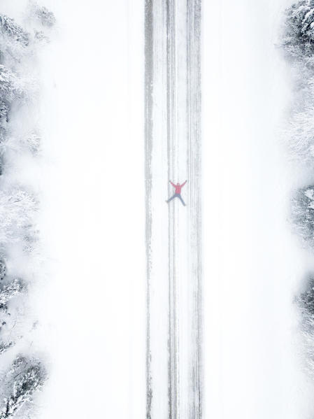 Aerial view of person lying down on snowy road, Pallas-Yllastunturi National Park, Muonio, Lapland, Finland