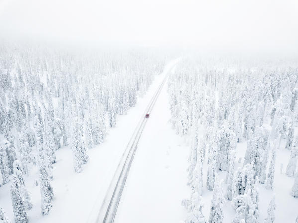 Aerial view of car along the snowy road in the icy forest, Pallas-Yllastunturi National Park, Muonio, Lapland, Finland