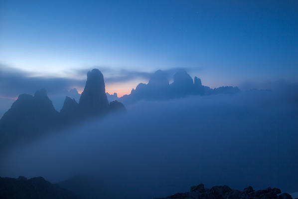 The Caldini of Misurina and the Tre Cime di Lavaredo (Dreizinnen) emerging out of a sea of fog at the twilight - Dolomites of Sesto, province of Belluno, Trentino Alto- Adige, Italy Europe