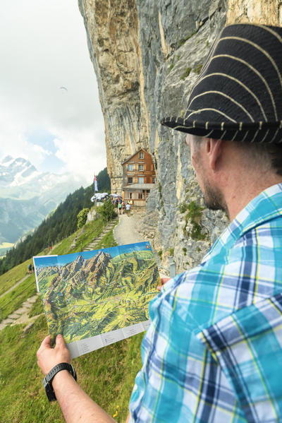 Man looks at map of hiking trails, Aescher-Wildkirchli Gasthaus, Ebenalp, Appenzell Innerrhoden, Switzerland