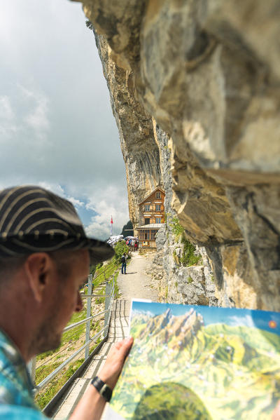 Man looks at map of hiking trails, Aescher-Wildkirchli Gasthaus, Ebenalp, Appenzell Innerrhoden, Switzerland