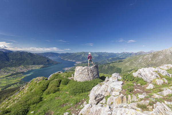 Hiker on summit of Monte Berlinghera looks towards Lake Como, Sondrio province, Lombardy, Italy