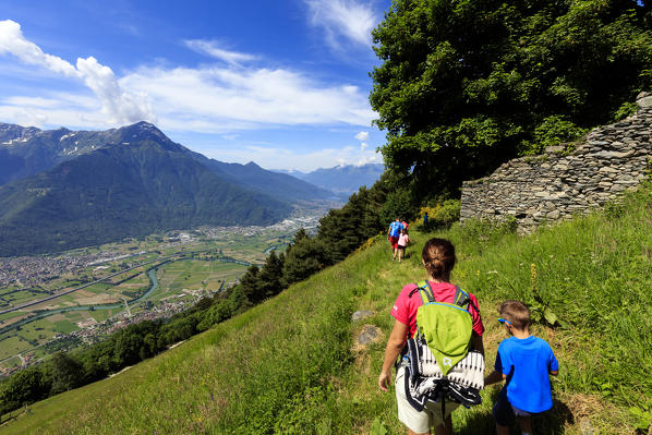 Family walk on footpath to Alpe Bassetta with Monte Legnone on background, Lower Valtellina, Sondrio province, Lombardy, Italy