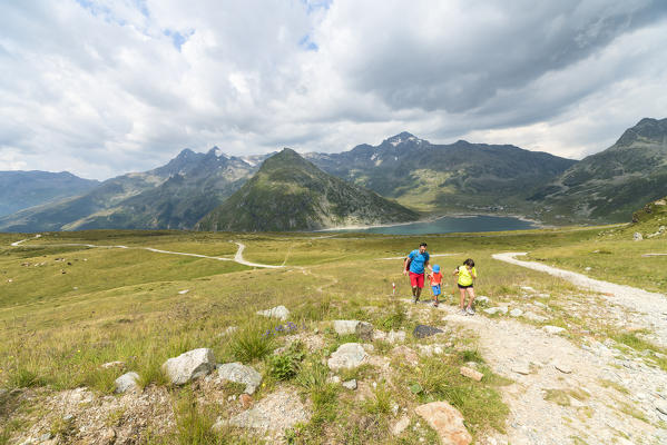 Father and children on footpath around Lake Montespluga, Andossi, Spluga Valley, Sondrio province, Valtellina, Lombardy, Italy