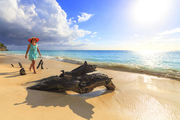 Woman with hat walks on Ffryes Beach, Antigua, Antigua and Barbuda, Leeward Islands, West Indies