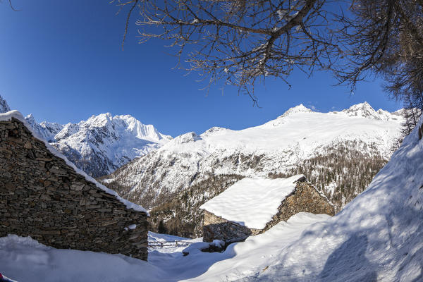 Huts covered with snow with Monte Disgrazia on background, Alpe dell'Oro, Valmalenco, Valtellina, Lombardy, Italy