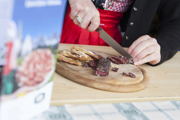 a model is cutting a piece of a typical homemade salami from South Tyrol, Bolzano province, Trentino Alto Adige, Italy, Europe