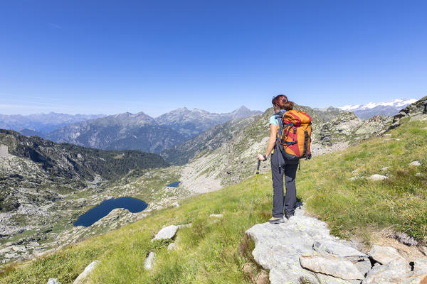 A girl is watching the Barma Lake near the Barma Refuge from a pass between the Aosta Valley and the mountains of Biella above Oropa; the Matterhorn and the Monte Rosa in the right. (Lys Valley, Gressoney, Aosta province, Aosta Valley, Italy, Europe)
