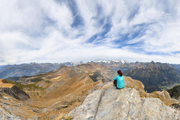 A girl is admiring the Alps from the Mont Blanc to the Monte Rosa from the Zerbion peak (Antagnod, Ayas Valley, Aosta province, Aosta Valley, Italy, Europe) (MR)