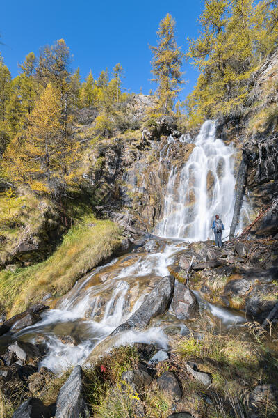 A girl is looking a waterfall near Torgnon (Valtournenche Valley, Aosta province, Aosta Valley, Italy, Europe) (MR)