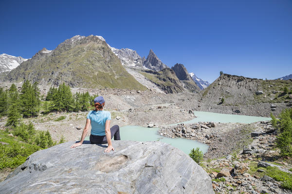 A girl relaxing in front of the Mont Blanc Massif and Miage Lake (Miage Lake, Veny Valley, Courmayeur, Aosta province, Aosta Valley, Italy, Europe)