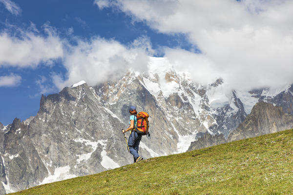 A trekker is walking in front of the Mont Blanc during the Mont Blanc hiking tours (Ferret Valley, Courmayeur, Aosta province, Aosta Valley, Italy, Europe) (MR)
