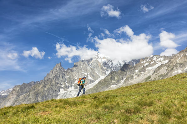 A trekker is walking in front of the Mont Blanc during the Mont Blanc hiking tours (Ferret Valley, Courmayeur, Aosta province, Aosta Valley, Italy, Europe) (MR)
