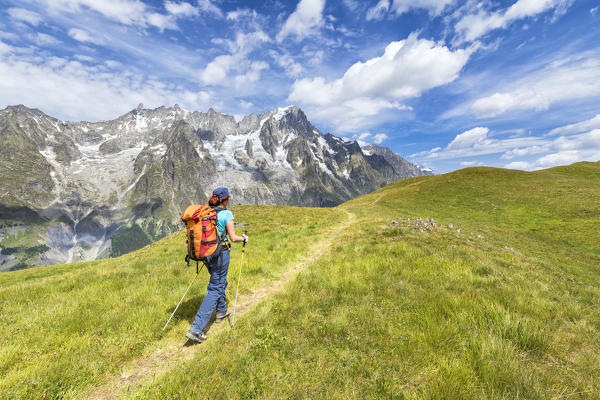 A trekker is walking on the Mont de la Saxe in front of Grandes Jorasses during during the Mont Blanc hiking tours (Ferret Valley, Courmayeur, Aosta province, Aosta Valley, Italy, Europe) (MR)
