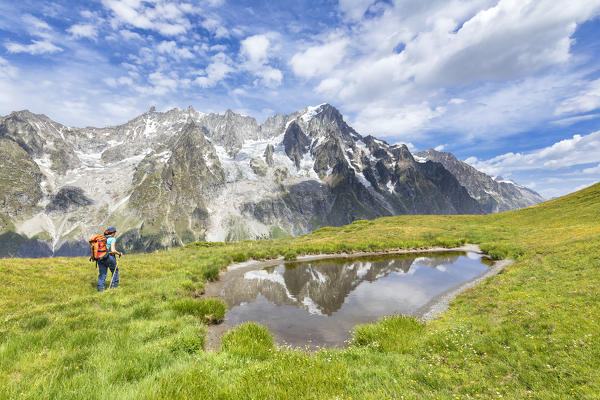 A trekker is walking on the Mont de la Saxe in front of Grandes Jorasses during during the Mont Blanc hiking tours (Ferret Valley, Courmayeur, Aosta province, Aosta Valley, Italy, Europe) (MR)
