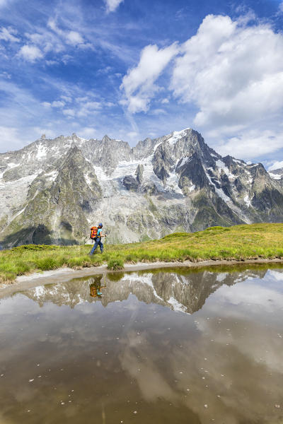 A trekker is walking on the Mont de la Saxe in front of Grandes Jorasses during the Mont Blanc hiking tours (Ferret Valley, Courmayeur, Aosta province, Aosta Valley, Italy, Europe) (MR)
