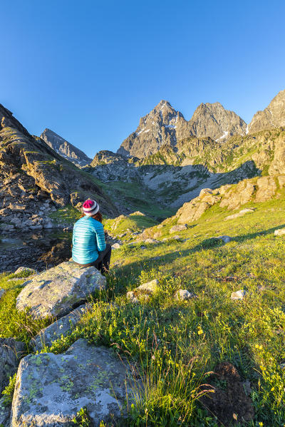 A girl is watching the Monviso Peak (Fiorenza Lake, Pian del Re, Monviso Natural Park, Po Valley, Crissolo, Cuneo province, Piedmont, Italy, Europe) (MR)