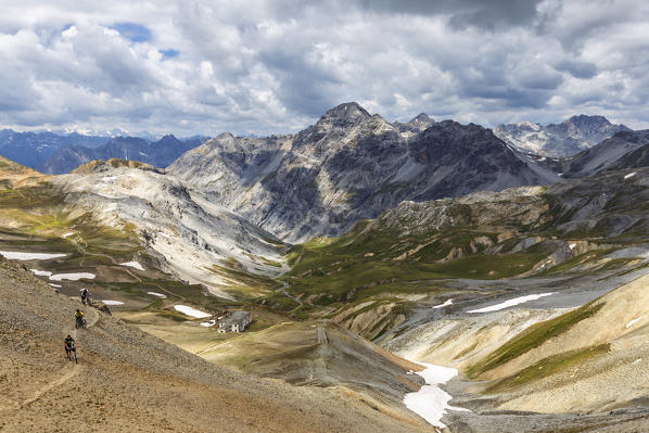 Bikers walks on a path in the high mountain. Passo dello Stelvio, National Park of Stelvio, Valtellina, Lombardy, Italy, Europe.