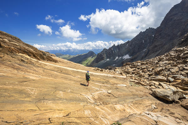 A hiker walks on the rock. Valmalenco, Valtellina, Lombardy, Italy, Europe.