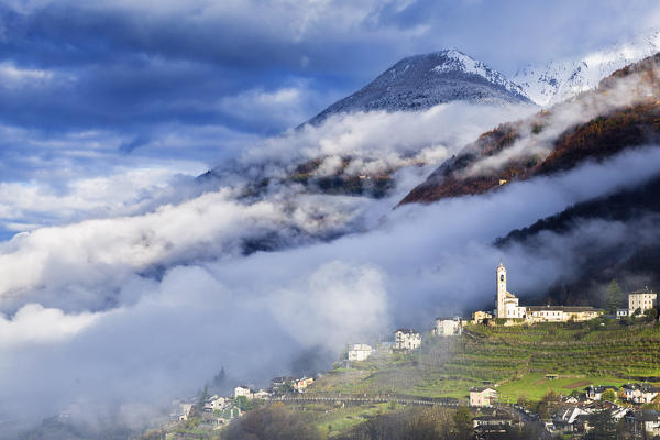 Mountain church between clouds and fog. Poggiridenti, Valtellina, Sondrio province, Italy, Europe.