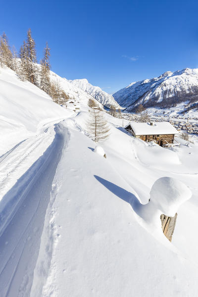 Winter path with a traditional hut in the winter scenery. Livigno, Valtellina, Lombardy, Italy, Europe.