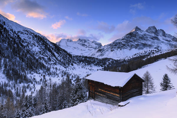 Traditional hut during a winter sunrise in Val Viola. Valdidentro, Valtellina, Lombardy, Italy, Europe.