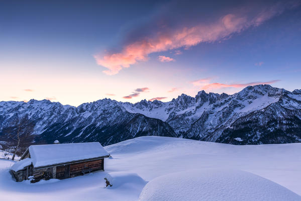 Stunning clouds above hut at sunrise. Soglio, Bregaglia Valley, Canton of Grisons, Switzerland, Europe.