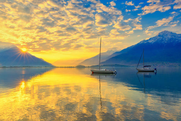 Colours of the sunrise is reflected in the water. Como Lake, Lombardy, Italy, Europe.