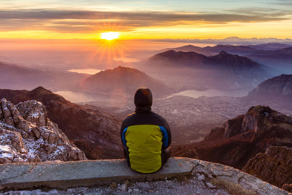 Hiker looks sunset from Mount Resegone. Lombardy, Italy, Europe.