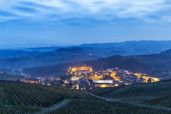 Village of Barolo during a foggy dusk with vineyards in the foreground. Barolo wine region, Langhe, Piedmont, Italy, Europe.