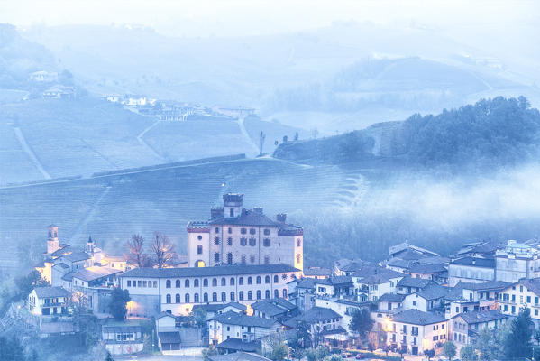 Castle and village of Barolo during a foggy dusk. Barolo wine region, Langhe, Piedmont, Italy, Europe.