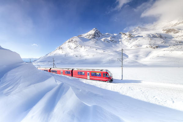 Bernina Express transit along Lago Bianco during winter blizzard , Bernina Pass, Engadin, Canton of Graubunden, Switzerland, Europe.