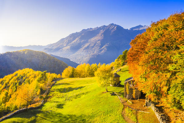 Autumnal fairytale landscape with strage lonely hut with colourful trees. Valtellina, Lombardy, Italy