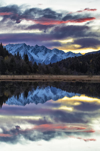 Adamello group is reflected in the Pian di Gembro pond at sunrise. Valtellina, Lombardy, Italy, Europe.