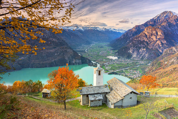 Autumn colors at the Foppaccia church at sunset with view on the Novate Lake and valley. Verceia, Valchiavenna, Valtellina, Lombardy, Italy.