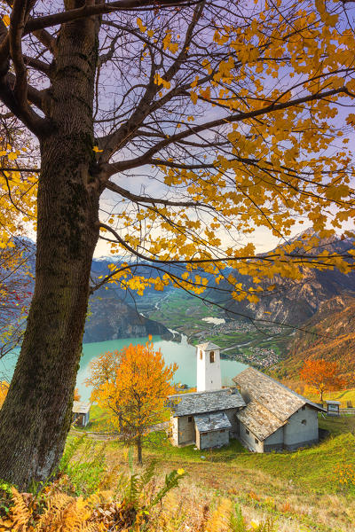 Autumn colors at the Foppaccia church at sunset with view on the Novate Lake and valley. Verceia, Valchiavenna, Valtellina, Lombardy, Italy.