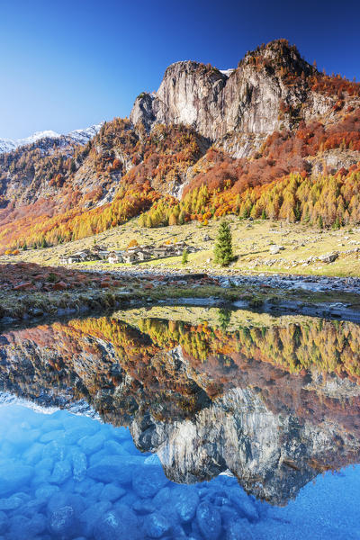 Village of Corte Terza and mountains is reflected in a clear puddle in autumn. Val Bodengo, Valchiavenna, Valtellina, Lombardy, Italy, Europe.