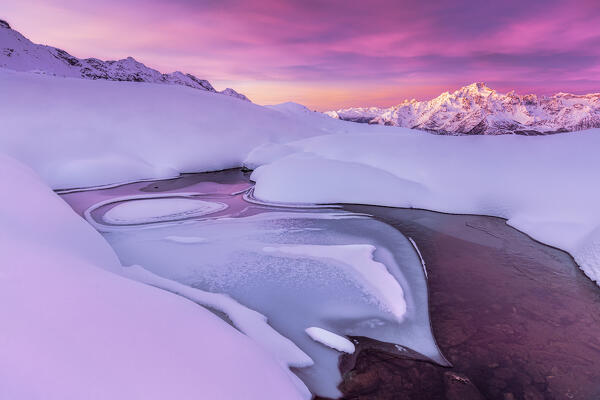 Crazy shape in a frozen alpine lake at sunrise with view on Mount Disgrazia. Valmalenco, Valtellina, Lombardy, Italy, Europe