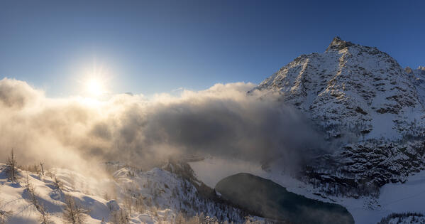 Panoramic view of Campomoro Lake and Sasso Moro illuminated by sun that filtered between black clouds. Valmalenco, Valtellina, Lombardy, Italy, Europe