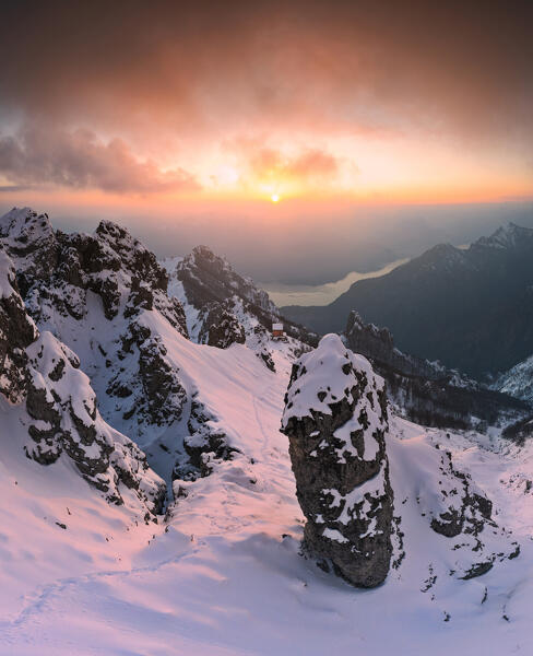 Fresh snow illuminates by warm sunset with view on Rifugio Rosalba and Lake Como. Grignetta, Grigne group, Lake Como, Lombardy, Italy, Europe