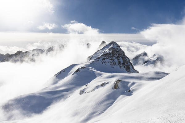 Piz Bardella between clouds in winter. Julier Pass, Canton of Graubunden, Switzerland, Europe.