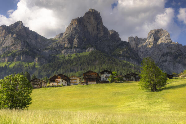 Traditional houses and meadows in a summer day with Dolomites in the background. Selva di Cadore, Val Fiorentina, Cadore, Belluno province,