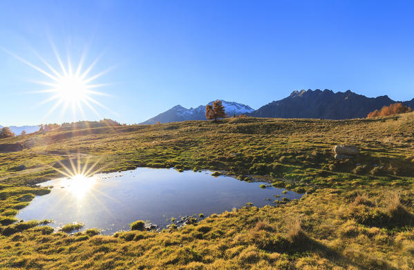 The sun reflects itself in a pond of Alpe Granda, Valtellina, Italy.