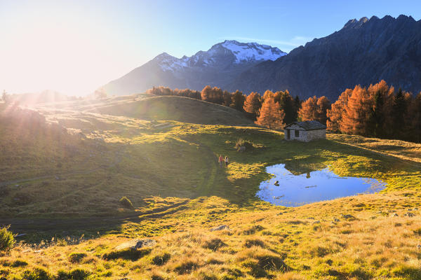 The sun illuminates the path of a couple at Alpe Granda, Valtellina, Italy.