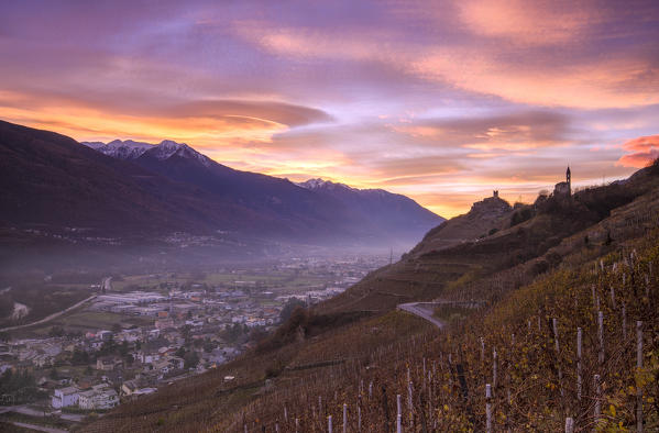 Sunset with lenticular clouds from wineyards that overlook Sondrio and Grumello Castle with Church of San Antonio. Montagna in Valtellina, Valtellina, Lombardy, Italy.