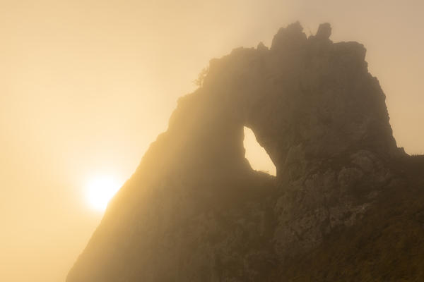 The sun illuminates the fog that hids Porta di Prada. Bocchetta di Prada, Grigna Settentrionale(Grignone), Northern Grigna Regional Park, Lombardy, Italy, Europe.