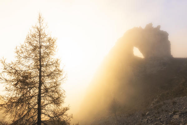 The sun illuminates the fog that hids Porta di Prada. Bocchetta di Prada, Grigna Settentrionale(Grignone), Northern Grigna Regional Park, Lombardy, Italy, Europe.