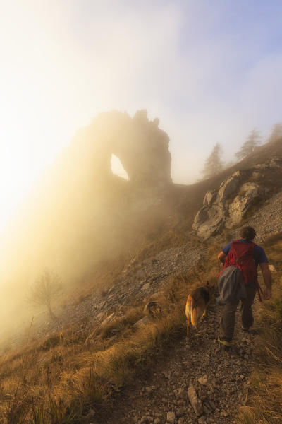 A trekker walks on the path to Porta di Prada, hidden by fog. Bocchetta di Prada, Grigna Settentrionale(Grignone), Northern Grigna Regional Park, Lombardy, Italy, Europe.