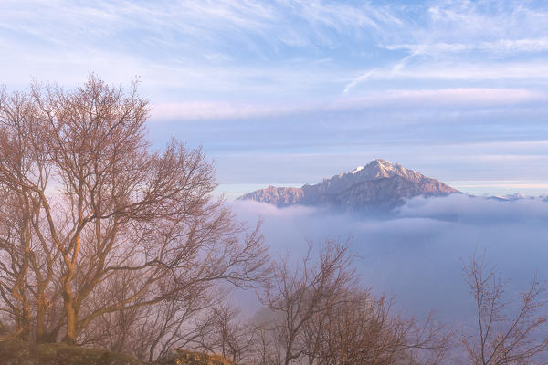 Foggy sunrise from the top of Monte Barro, with the Grignetta in the background. Monte Barro Regional Park, Brianza, Lombardy, Italy, Europe.